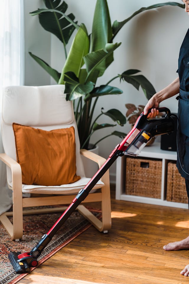 Produk cordless vacuum Terbaik - Photo by Liliana Drew: https://www.pexels.com/photo/person-in-black-t-shirt-and-black-pants-holding-black-and-red-vacuum-cleaner-9462146/